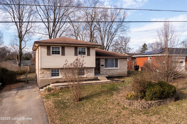 tri-level home with stone siding and a front lawn