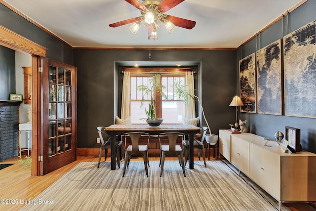 dining space featuring crown molding, wood finished floors, ceiling fan, and baseboards