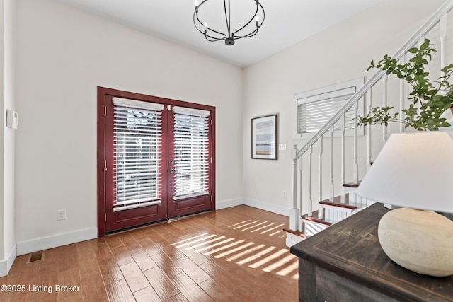 foyer with stairs, baseboards, wood finished floors, and a notable chandelier