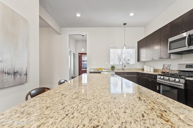 kitchen featuring decorative light fixtures, a breakfast bar area, recessed lighting, appliances with stainless steel finishes, and a sink