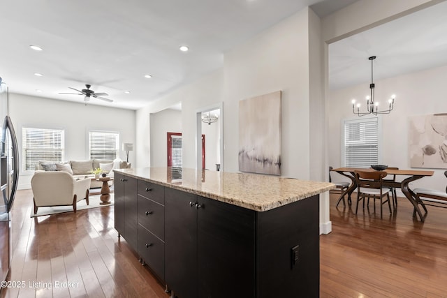 kitchen with recessed lighting, dark wood-style flooring, a kitchen island, open floor plan, and hanging light fixtures