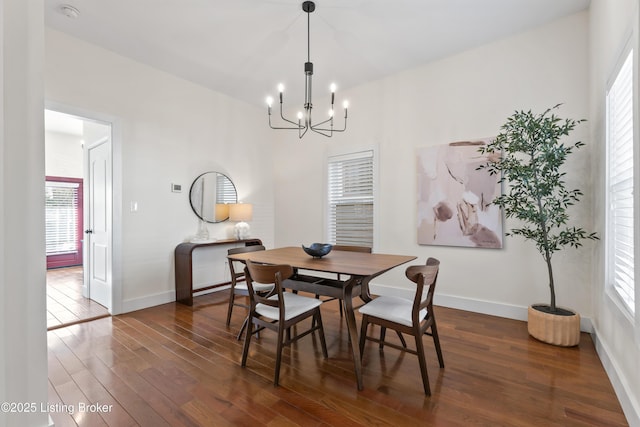 dining space featuring dark wood-type flooring, an inviting chandelier, and baseboards