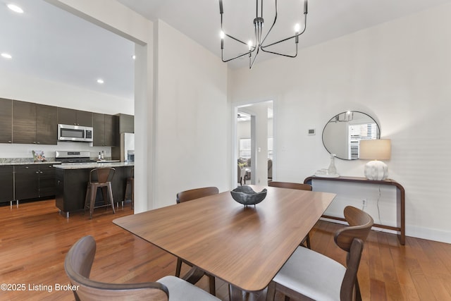 dining room featuring hardwood / wood-style flooring, baseboards, a notable chandelier, and recessed lighting