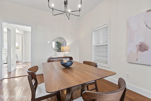 dining area featuring baseboards, a chandelier, and wood finished floors