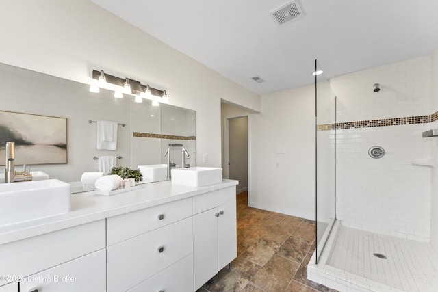 full bath with double vanity, a shower stall, visible vents, and a sink