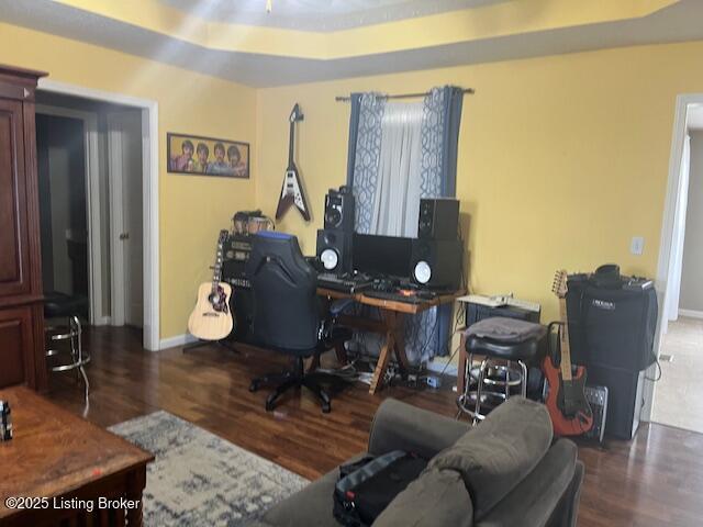 office with a tray ceiling, baseboards, and wood finished floors