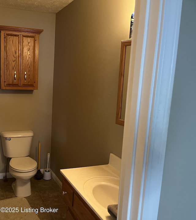 half bath featuring toilet, vanity, baseboards, and tile patterned floors