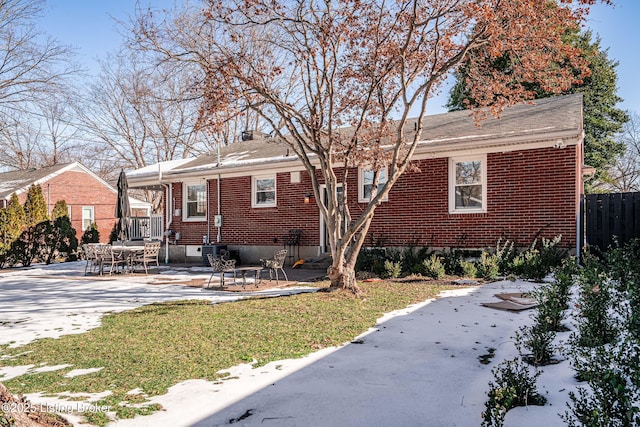 view of front of home featuring brick siding, a patio, a chimney, and fence