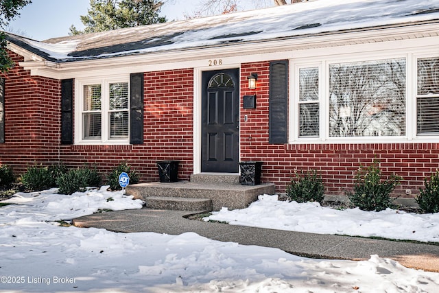 snow covered property entrance with brick siding