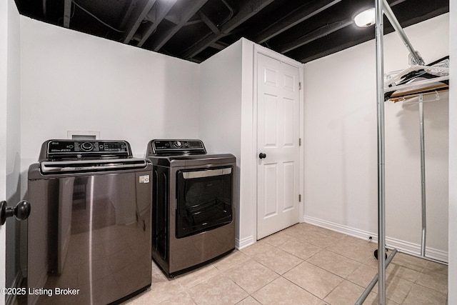 washroom featuring washing machine and dryer, laundry area, and light tile patterned floors