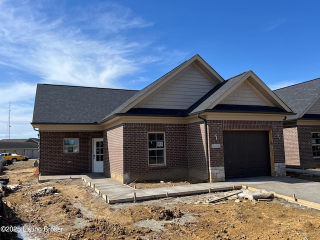 view of front facade featuring aphalt driveway, an attached garage, brick siding, and a shingled roof