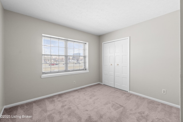 unfurnished bedroom with a textured ceiling, a closet, carpet, and baseboards