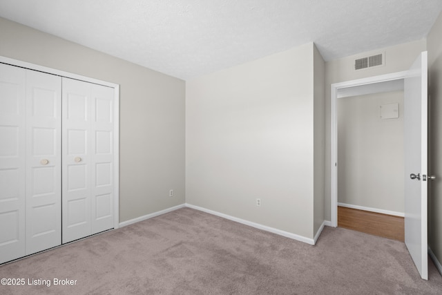 unfurnished bedroom with carpet, a closet, visible vents, and baseboards