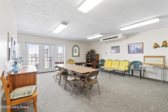 carpeted dining space with a textured ceiling, an AC wall unit, and french doors