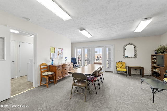 dining room featuring french doors, light colored carpet, and a textured ceiling