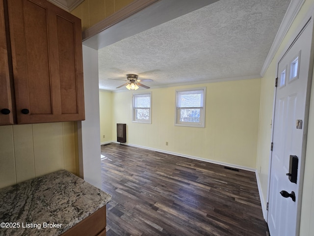 interior space featuring crown molding, light countertops, dark wood-type flooring, brown cabinetry, and a textured ceiling