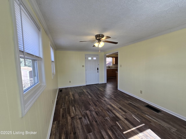 unfurnished room featuring ceiling fan, dark wood-style flooring, a sink, visible vents, and ornamental molding