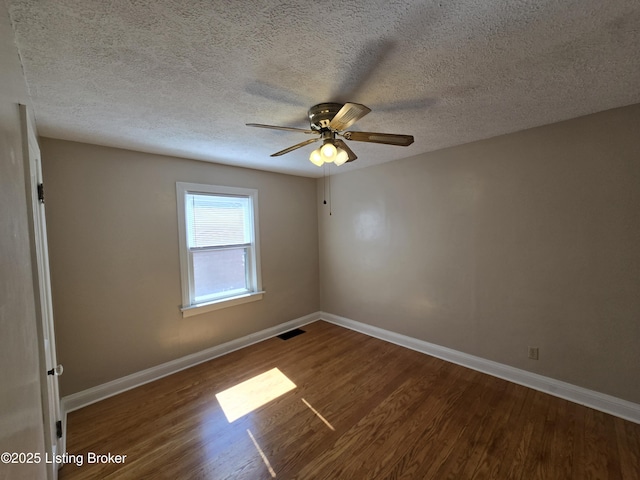 unfurnished room featuring dark wood-style floors, baseboards, and visible vents