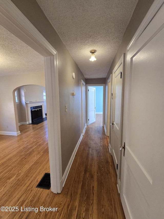 hallway featuring a textured ceiling, baseboards, and wood finished floors