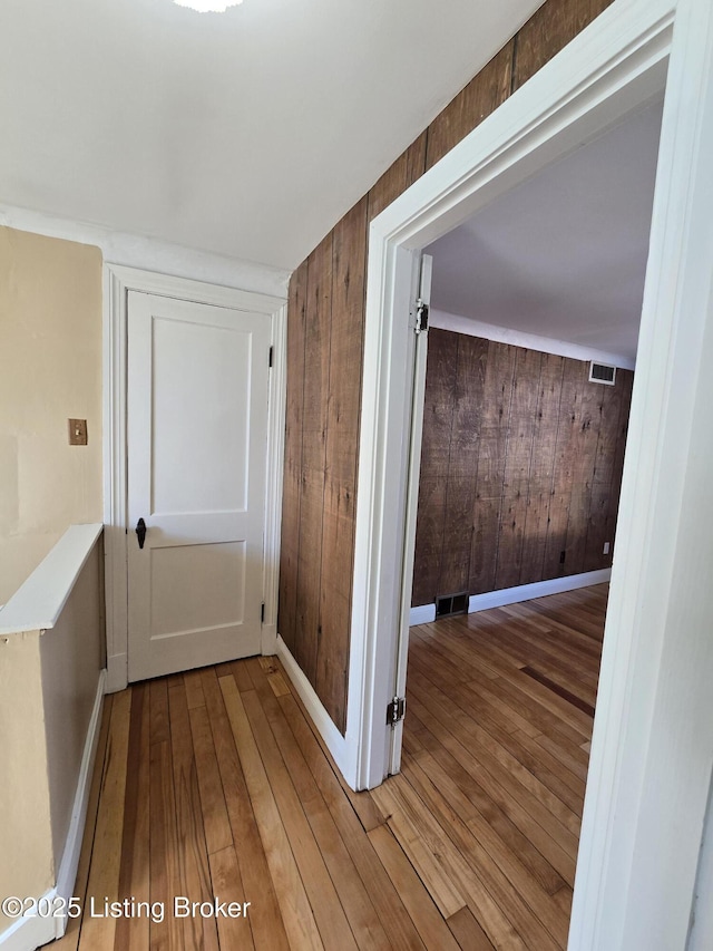 corridor with wood walls, baseboards, and wood finished floors