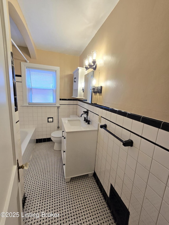 full bath featuring toilet, a wainscoted wall, tile walls, and vanity