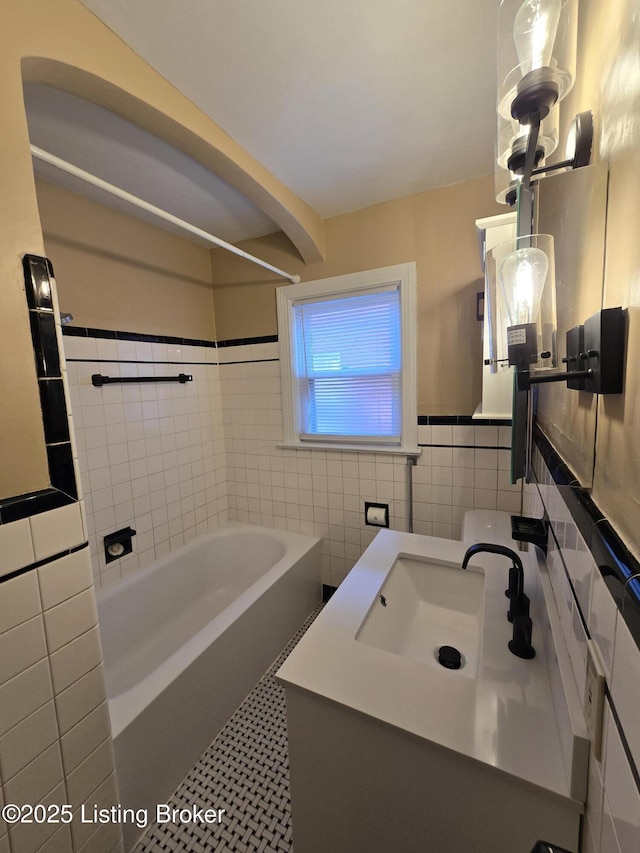 bathroom with wainscoting, tile walls, vanity, and bathing tub / shower combination