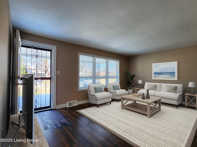 living room with wood finished floors, visible vents, and baseboards