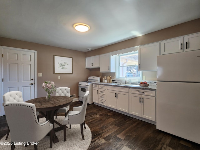 kitchen with dark wood-type flooring, white cabinets, a sink, light stone countertops, and white appliances