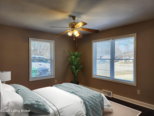 bedroom with dark wood-style floors, baseboards, visible vents, and a ceiling fan