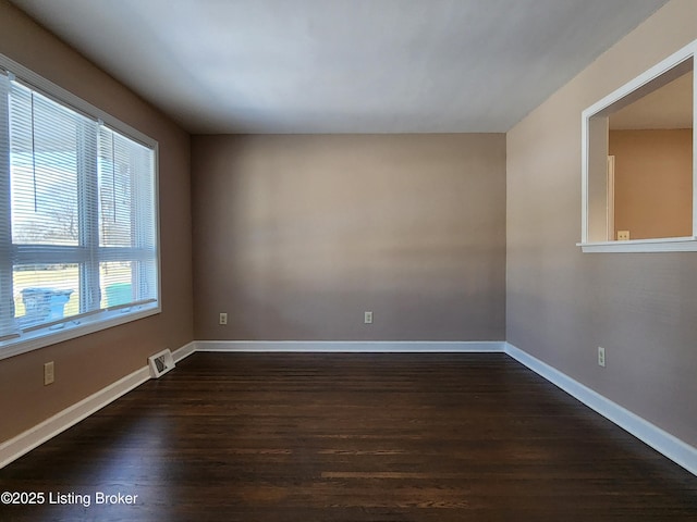 unfurnished room featuring baseboards, visible vents, and dark wood-type flooring