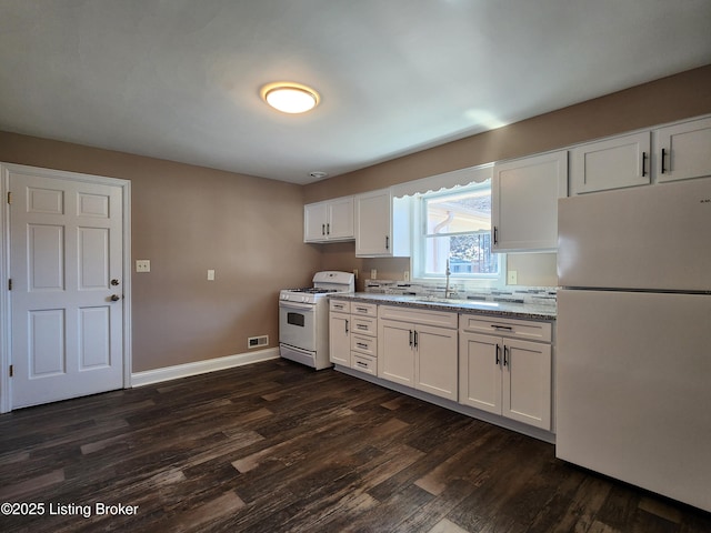 kitchen with light stone counters, white appliances, dark wood-type flooring, a sink, and white cabinets