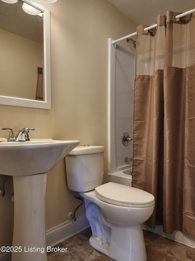 full bath featuring baseboards, a sink, toilet, and shower / bath combo with shower curtain