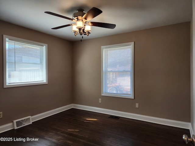 empty room with baseboards, visible vents, dark wood finished floors, and a ceiling fan