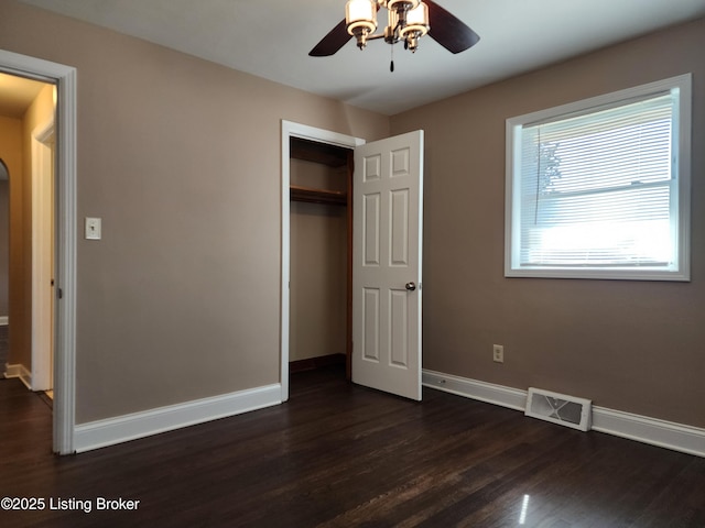 unfurnished bedroom with dark wood finished floors, a closet, visible vents, a ceiling fan, and baseboards