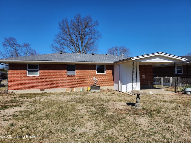 back of property featuring brick siding, a yard, central air condition unit, a shingled roof, and fence