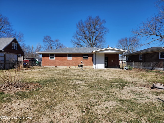 back of property with a yard, fence, and brick siding