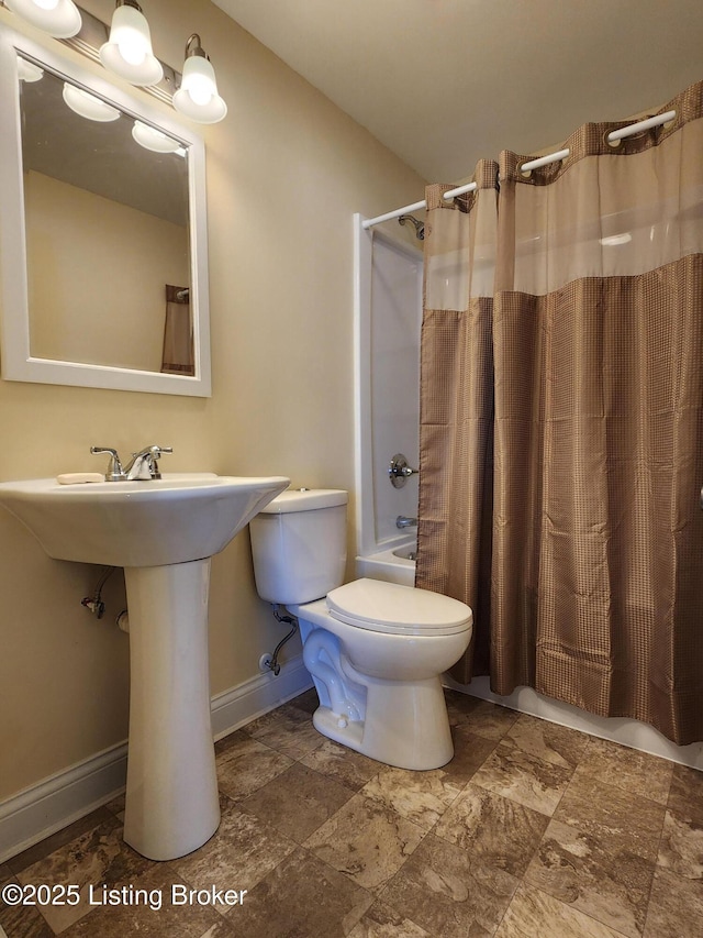 bathroom with baseboards, a sink, toilet, and shower / bathtub combination with curtain