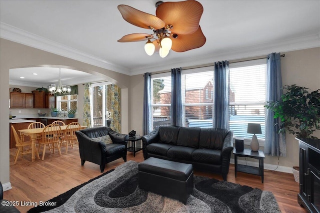 living room with crown molding, baseboards, arched walkways, and light wood-style floors