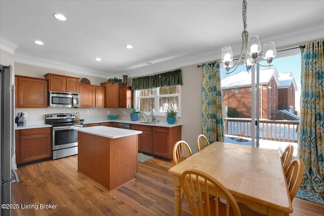 kitchen with a center island, pendant lighting, stainless steel appliances, light countertops, and a sink