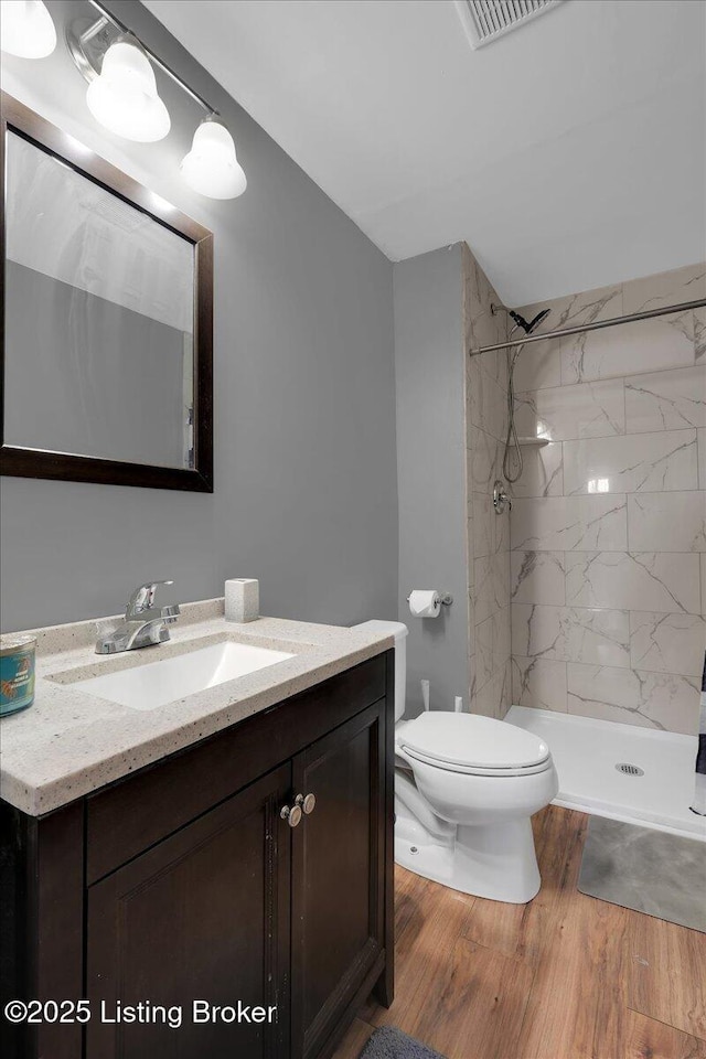 full bath featuring visible vents, toilet, wood finished floors, vanity, and a shower stall