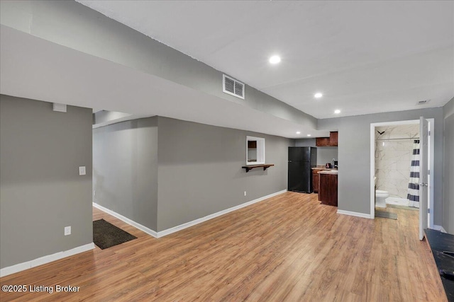 unfurnished living room with light wood-type flooring, visible vents, and baseboards