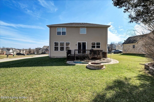 back of house with a residential view, a fire pit, a deck, and a yard