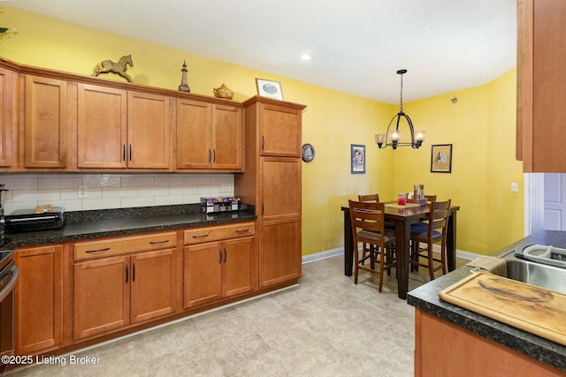 kitchen with tasteful backsplash, dark countertops, decorative light fixtures, and brown cabinets