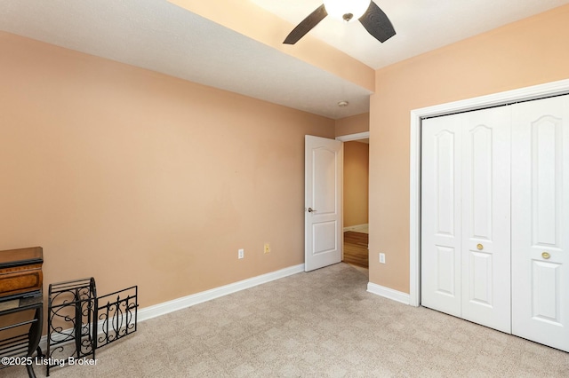 unfurnished bedroom with baseboards, a closet, a ceiling fan, and light colored carpet