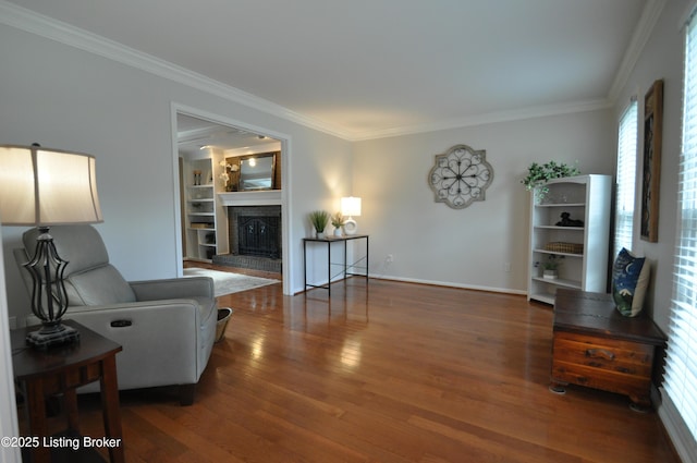 living room with a fireplace, wood finished floors, baseboards, built in features, and crown molding