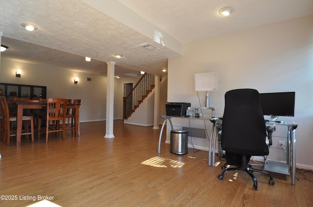 office featuring decorative columns, a textured ceiling, and wood finished floors