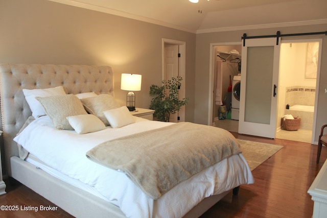 bedroom with crown molding, a closet, a spacious closet, a barn door, and washer / dryer