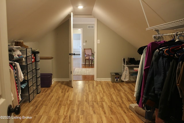 walk in closet featuring light wood-style floors, visible vents, and vaulted ceiling