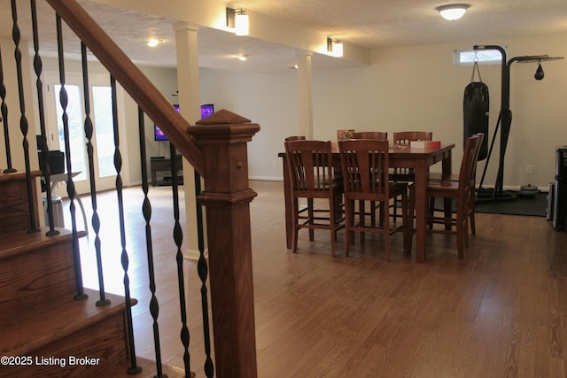 dining area with a textured ceiling, stairs, baseboards, and wood finished floors