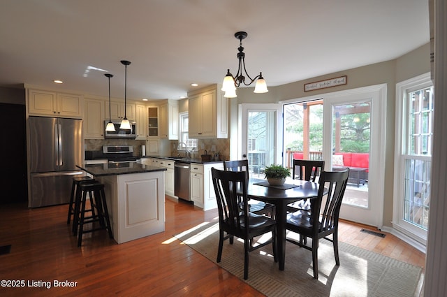 dining space with wood-type flooring, visible vents, a notable chandelier, and recessed lighting